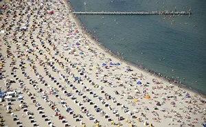 Sunbathers and roofed wicker beach chairs are seen along the beach on the bay of Sunbathers and roofed wicker beach chairs are seen along the beach on the bay of
