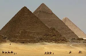 Tourists ride camels in front of Giza pyramids Tourists ride camels in front of Giza pyramids