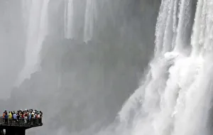 Tourists stand at the end of a catwalk on the Brazilian side of the Iguazu river to Tourists stand at the end of a catwalk on the Brazilian side of the Iguazu river to