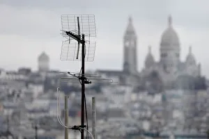 A tv antenna is seen on the rooftops of residential buildings in front of the Sacre Coeur A tv antenna is seen on the rooftops of residential buildings in front of the Sacre Coeur