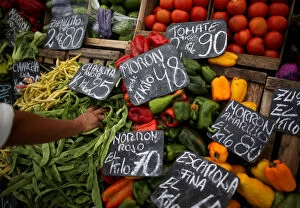 Images Dated 17th April 2019: A vegetable seller grabs a handful of indian beans at a street market, in Buenos Aires