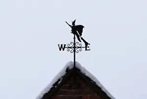 A weathervane in the shape of a witch on a broomstick is seen on the snow-covered roof of A weathervane in the shape of a witch on a broomstick is seen on the snow-covered roof of