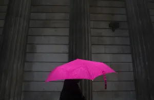 A woman carries an umbrella during a rain shower as she walks past the Bank of England A woman carries an umbrella during a rain shower as she walks past the Bank of England