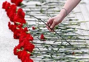 A woman places a red carnation flower on the ground by a pool outside the Scottish A woman places a red carnation flower on the ground by a pool outside the Scottish