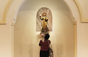 A woman prays as she holds her dog, after getting it blessed by a priest A woman prays as she holds her dog, after getting it blessed by a priest