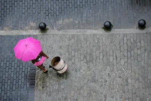 Woman pulls a barrel on a wheel-cart through the rain in Havana Woman pulls a barrel on a wheel-cart through the rain in Havana