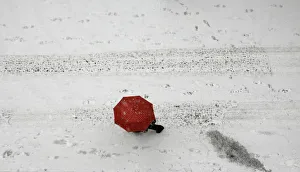 A woman shields herself under an umbrella as she walks during a heavy snowfall in A woman shields herself under an umbrella as she walks during a heavy snowfall in