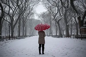 A woman stands with an umbrella during snowfall at Central Park in New York A woman stands with an umbrella during snowfall at Central Park in New York