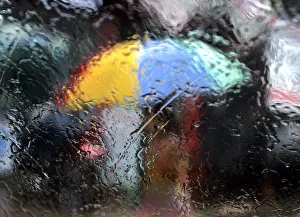 A woman walking with an umbrella is seen from a window as it rains during the monsoon A woman walking with an umbrella is seen from a window as it rains during the monsoon