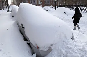 A woman walks past a row of cars buried in the snow in Hoboken A woman walks past a row of cars buried in the snow in Hoboken