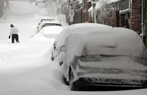 A woman walks up a snow filled street in Boston A woman walks up a snow filled street in Boston