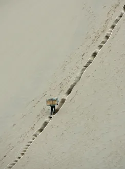 A worker carries sleds up the Mingsha Sand Dunes on the outskirts of Dunhuang A worker carries sleds up the Mingsha Sand Dunes on the outskirts of Dunhuang