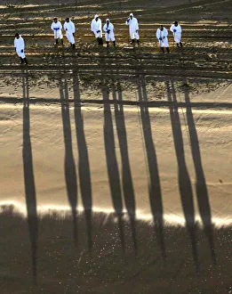 WORKERS CAST SHADOWS ON A CLEAN BEACH IN THE SPANISH NORTHERN COAST WORKERS CAST SHADOWS ON A CLEAN BEACH IN THE SPANISH NORTHERN COAST