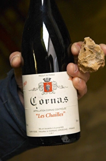 Alberic Mazoyer showing in his hand a bottle of Cornas les Chailles and a stone Alberic Mazoyer showing in his hand a bottle of Cornas les Chailles and a stone