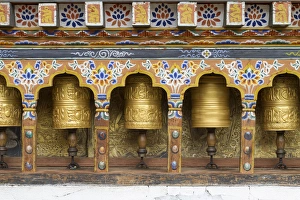 Bhutan. Spinning prayer wheels along a temple wall Bhutan. Spinning prayer wheels along a temple wall