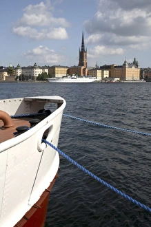 A boat in Sodermalm Island dock with Riddarholmen Island and the black spire of Riddarholmskyrkan A boat in Sodermalm Island dock with Riddarholmen Island and the black spire of Riddarholmskyrkan