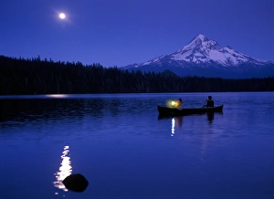 Two boys in canoe with lantern at night on Lost Lake with Mt Hood in the background Two boys in canoe with lantern at night on Lost Lake with Mt Hood in the background
