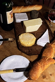 Brusvily, Britanny, France. Cheeses on a cheese board, bread, knife, bottle and glass Brusvily, Britanny, France. Cheeses on a cheese board, bread, knife, bottle and glass