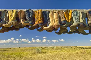 Canada, Saskatchewan, Great Sand Hills. Old cowboy boots on posts on prairie. Credit as Canada, Saskatchewan, Great Sand Hills. Old cowboy boots on posts on prairie. Credit as
