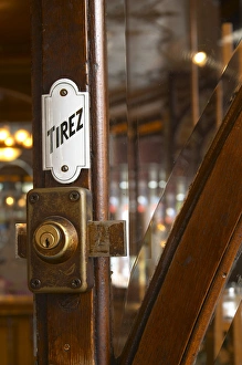 Detail of a door with a brass lock an enamel sign saying tirez (pull) Detail of a door with a brass lock an enamel sign saying tirez (pull)