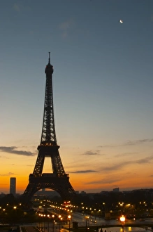 The Eiffel Tower in Paris in early morning, pale blue sky some white clouds and the The Eiffel Tower in Paris in early morning, pale blue sky some white clouds and the