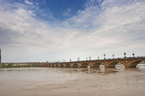 The famous old Pont de Pierre bridge across the Garonne river and the city at the The famous old Pont de Pierre bridge across the Garonne river and the city at the