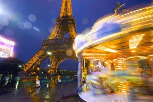 France, Paris. Eiffel Tower in twilight fog and rain at twilight with a merry-go-round France, Paris. Eiffel Tower in twilight fog and rain at twilight with a merry-go-round