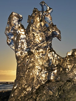Golden sunrise seen through iceberg formation on the beach at Jokulsarlon, Iceland Golden sunrise seen through iceberg formation on the beach at Jokulsarlon, Iceland