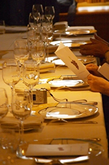 A guest holding up and reading the menu in anticipation of the meal. In the restaurant A guest holding up and reading the menu in anticipation of the meal. In the restaurant