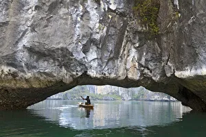 Ha Long Bay, Vietnam. View of kayaker through limestone arch Ha Long Bay, Vietnam. View of kayaker through limestone arch