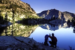 Hiker at sunset overlooking Looking Glass Lake in the Eagle Cap Wilderness, Oregon Hiker at sunset overlooking Looking Glass Lake in the Eagle Cap Wilderness, Oregon