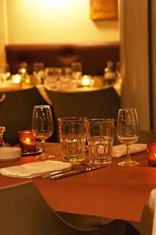 Interior of The restaurant Brunel at night. Tables with glasses, knives, ofrks, glasses Interior of The restaurant Brunel at night. Tables with glasses, knives, ofrks, glasses