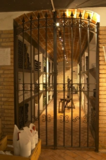 An iron gate leading in to the private wine cellar with aging bottles An iron gate leading in to the private wine cellar with aging bottles