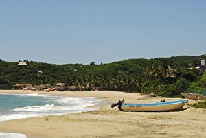 Mexico, Mazunte, view of a nautical vessel moored on sand at the shore of the beach with trees Mexico, Mazunte, view of a nautical vessel moored on sand at the shore of the beach with trees