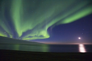 The moon shines down on the Arctic Ocean as curtains of green Aurora Borealis dance overhead The moon shines down on the Arctic Ocean as curtains of green Aurora Borealis dance overhead