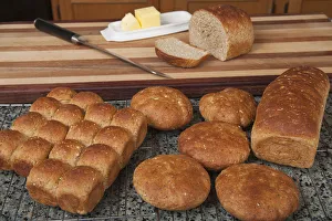 Multigrain rolls, buns and loaf with a slice cut off, with butter and a bread knife Multigrain rolls, buns and loaf with a slice cut off, with butter and a bread knife