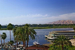 Nile River and docked sightseeing boats, and distant Valley of the Kings, from modern Nile River and docked sightseeing boats, and distant Valley of the Kings, from modern