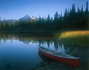 Red canoe pulled on shore of Sparks Lake with early morning light filtering across Red canoe pulled on shore of Sparks Lake with early morning light filtering across