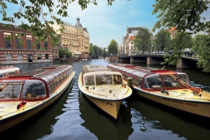 Refurbished old canal cruise boats moored along Amstel canal in Amsterdam, The Netherlands Refurbished old canal cruise boats moored along Amstel canal in Amsterdam, The Netherlands