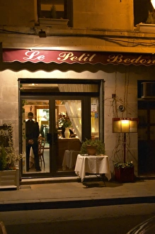 The restaurant Le Petit Bedon at night with the waiter standing inside the door. Avignon The restaurant Le Petit Bedon at night with the waiter standing inside the door. Avignon
