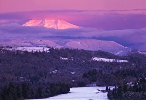 Sunrise on a snow covered landscape with Mt Hood peeking through clouds, as viewed Sunrise on a snow covered landscape with Mt Hood peeking through clouds, as viewed