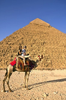 Tourists ride a camel in front of the Great Pyramids of Egypt in Cairo on the Giza Tourists ride a camel in front of the Great Pyramids of Egypt in Cairo on the Giza