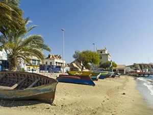 Traditional fishing boats on the beach of the harbor, landmark Torre de Belem in the Traditional fishing boats on the beach of the harbor, landmark Torre de Belem in the