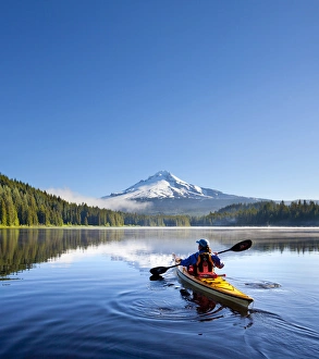 USA, Oregon. A woman in a sea kayak paddles on Trillium Lake, Oregon, in the Oregon Cascades USA, Oregon. A woman in a sea kayak paddles on Trillium Lake, Oregon, in the Oregon Cascades