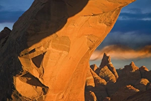 USA, Utah, Arches National Park. Setting sun illumines Skyline Arch, boulders, and spiral cloud USA, Utah, Arches National Park. Setting sun illumines Skyline Arch, boulders, and spiral cloud