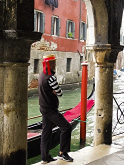 Venice, Italy. Gondolier man looks out onto the canal next to his gondola Venice, Italy. Gondolier man looks out onto the canal next to his gondola