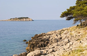 View over coast cliffs with pine trees over the sea water towards an island. Prizba village View over coast cliffs with pine trees over the sea water towards an island. Prizba village