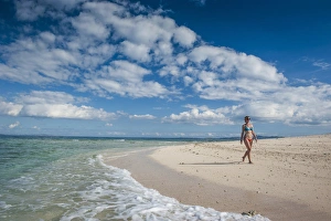 Woman walking along the white sand beach of Beachcomber island, Mamanucas islands Woman walking along the white sand beach of Beachcomber island, Mamanucas islands