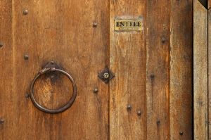 The wooden entrance door with metal ring knocker and old lock, sign saying entree, step in The wooden entrance door with metal ring knocker and old lock, sign saying entree, step in