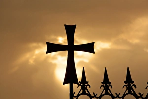 A wrought-iron cross on a fence in Syria at sunrise A wrought-iron cross on a fence in Syria at sunrise